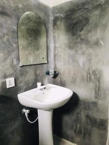 een badkamer met een witte wastafel en een spiegel bij Nature Inn in Mirissa