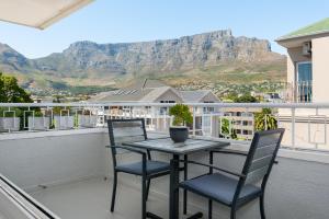 una mesa y sillas en un balcón con una montaña en Buitenhof 301 en Ciudad del Cabo