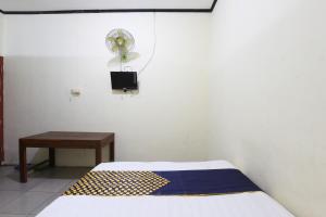 a bedroom with a bed and a table and a fan at OYO 92231 Penginapan Tanjung Alang Syariah in Makassar