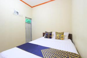 a bedroom with a bed with blue and yellow pillows at OYO 92231 Penginapan Tanjung Alang Syariah in Makassar