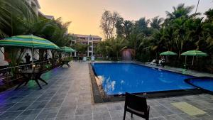 a swimming pool with chairs and umbrellas next to a resort at SUN N SEA Resort in Diveagar