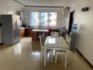 cocina con mesa blanca y nevera en Masaki Anne H & Apartment, en Dar es Salaam