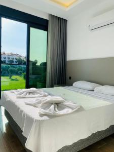 sypialnia z łóżkiem z białą pościelą i oknem w obiekcie İSTANBUL BEACH HOTEL SWEET HOME w mieście Kemer
