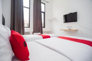 a hotel room with two beds and a flat screen tv at RedDoorz at Jalan Bangau Palembang in Palembang