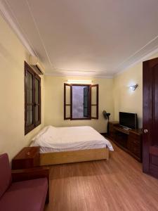 a bedroom with a bed and a tv and a couch at French-styled house in Hanoi