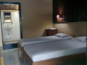 a bedroom with two twin beds and a bathroom at Ue Datu Cottages in Tentena