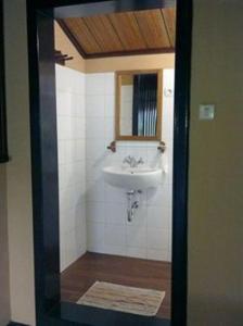 ein Bad mit einem Waschbecken und einem Spiegel in der Unterkunft Ue Datu Cottages in Tentena