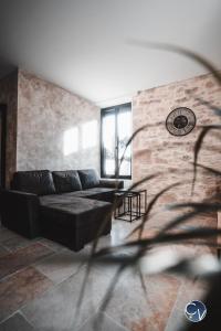 uma sala de estar com um sofá e um relógio numa parede de tijolos em Mazet en pierre avec jardin privatif em Sernhac