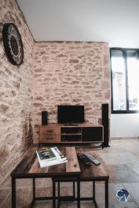 uma sala de estar com uma mesa de madeira e uma televisão em Mazet en pierre avec jardin privatif em Sernhac