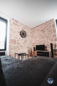 a bedroom with a brick wall with a clock on the wall at Mazet en pierre avec jardin privatif in Sernhac