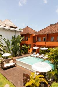 an outdoor pool with chairs and umbrellas next to a house at The Room Padang-Padang in Uluwatu