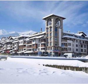 a large building with a clock tower in the snow at Boutique lux design apartment @Bansko Royal Towers in Bansko