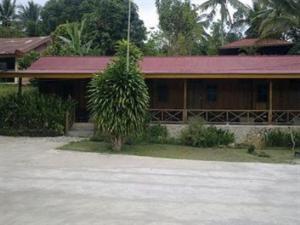 a house with a tree in front of it at Ue Datu Cottages in Tentena