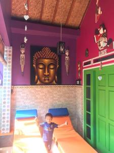 a little boy standing in a room with a giant head on the wall at Kubu Pilatus – Family House Lombok in Tjakranegara