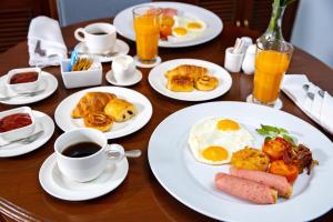 a wooden table with plates of breakfast foods and cups of coffee at Chatrium Hotel Royal Lake Yangon in Yangon