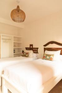 two beds in a white bedroom with a chandelier at The Room Padang-Padang in Uluwatu
