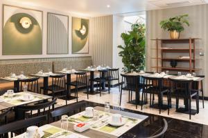 a dining room with tables and chairs and plants at Hotel Khla Nice in Nice