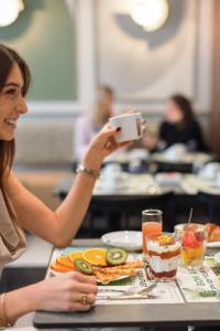 a woman taking a picture of a plate of food at Hotel Khla Nice in Nice