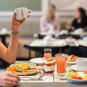 a woman taking a picture of a table with food and drinks at Hotel Khla Nice in Nice