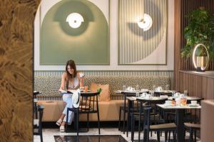 a woman sitting at a table in a restaurant at Hotel Khla Nice in Nice