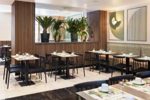 a restaurant with tables and chairs and plants at Hotel Khla Nice in Nice