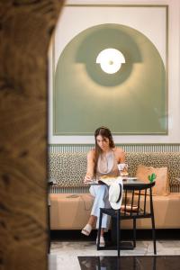 a woman sitting on a couch reading a book at Hotel Khla Nice in Nice