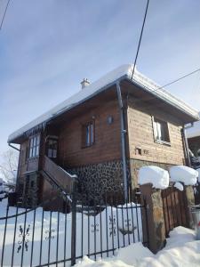 een houten huis met een hek in de sneeuw bij Chalupa Soľ nad zlato in Lazisko