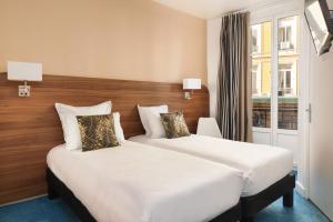 a hotel room with two beds and a window at Hotel Khla Nice in Nice