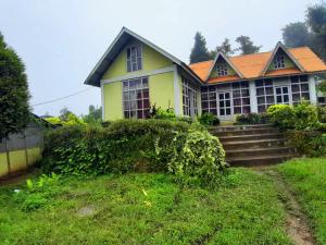 een geel huis met een oranje dak bij Snow White Holiday Inn Homestay in Kalimpong