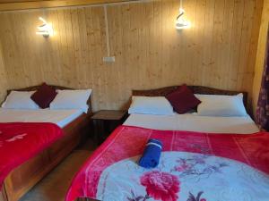 twee bedden in een kamer met houten wanden bij Snow White Holiday Inn Homestay in Kalimpong