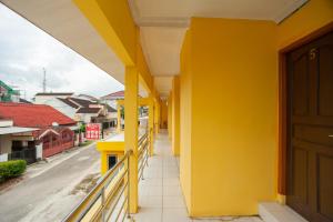um edifício amarelo com colunas amarelas numa rua em RedDoorz Syariah at Jalan Wayhitam Palembang em Palimbão