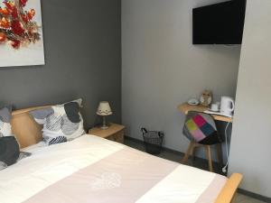 - une chambre avec un lit et un bureau avec une télévision dans l'établissement Relais Vosges Alsace, à Plainfaing