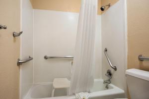 a bathroom with a white shower curtain and a toilet at Days Inn by Wyndham Dallas Irving in Irving