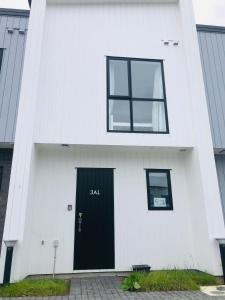 een wit huis met een zwarte deur en ramen bij Cozy Brand New Townhouse 26 in Auckland