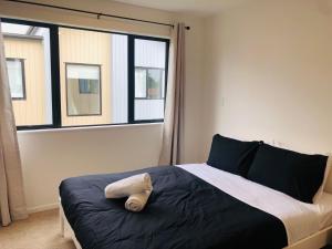 een slaapkamer met een bed en een raam bij Cozy Brand New Townhouse 26 in Auckland