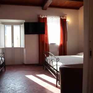 a bedroom with a bed and windows and a television at La Bolgora Guesthouse in Novara