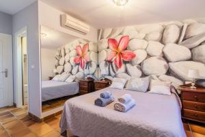 1 dormitorio con 2 camas y flores en la pared en Chalet El Santiscal, en Arcos de la Frontera