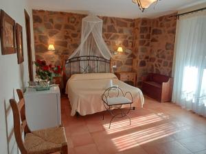 een slaapkamer met een bed, een tafel en een stoel bij Hotel Villa de Berzocana in Berzocana
