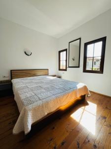 a bedroom with a bed and two windows at Къща за гости Под Манастира in Skrino