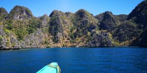 Ein Boot im Wasser vor einem Haufen Berge in der Unterkunft Rain Haven Lodging House in Coron