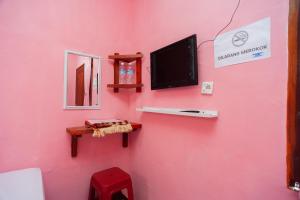 a pink wall with a flat screen tv on it at RedDoorz near Simpang Bandara SMB II in Palembang +14 photos
