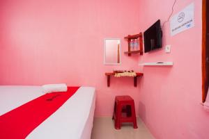 a pink room with a bed and a tv at RedDoorz near Simpang Bandara SMB II in Palembang
