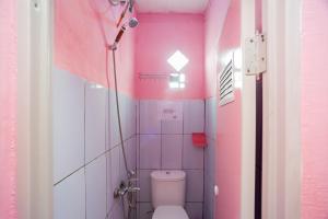 a pink bathroom with a toilet in a room at RedDoorz near Simpang Bandara SMB II in Palembang