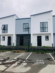 um parque de estacionamento em frente a dois edifícios brancos em Cozy Brand New Townhouse 27 em Auckland