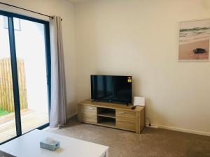 uma sala de estar com uma televisão de ecrã plano num armário de madeira em Cozy Brand New Townhouse 27 em Auckland