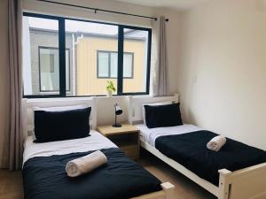 duas camas num quarto com duas janelas em Cozy Brand New Townhouse 27 em Auckland