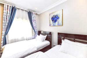 two beds in a room with a window at Cosy modern apartment in Naalya in Kampala
