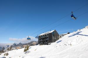 a ski lift over a snow covered slope with a building at BÚDA Jasná in Belá