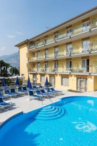 un hotel con piscina e sedie e un edificio di Hotel Drago - Garda Lake Collection a Brenzone sul Garda