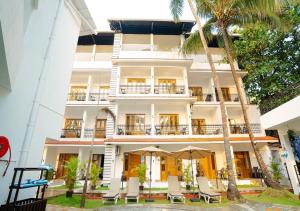 a large white building with palm trees in front of it at The Verda De Miranda Resort Morjim North Goa in Morjim